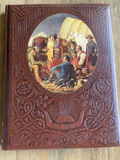 a leather book with a painting on the cover