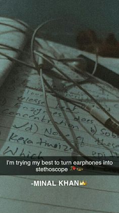 an open notebook with writing on it and headphones attached to the book's cover