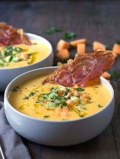 two white bowls filled with soup and garnished with bacon