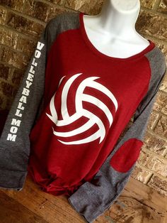 a red and gray shirt with white volleyball on the front is sitting on a mannequin's head