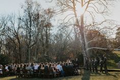 a group of people standing around each other in front of a tree with the sun shining on them