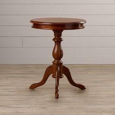 a small wooden table on a hard wood floor with white walls in the backround