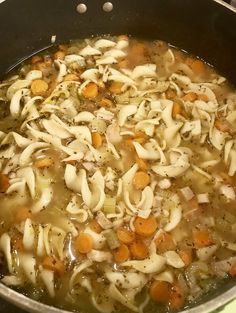 a pot filled with noodles and carrots on top of a stove