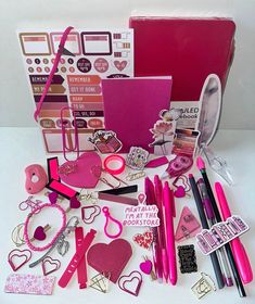 a pink box filled with lots of different types of crafting supplies and accessories on top of a white table