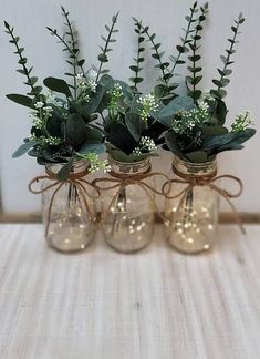 four glass vases with plants in them on a table