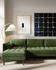 a green couch sitting next to a lamp in a living room