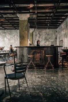 an empty room with chairs and a bar in the middle that has people sitting at it