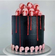 a black cake with red icing and skulls on the top is sitting on a plate