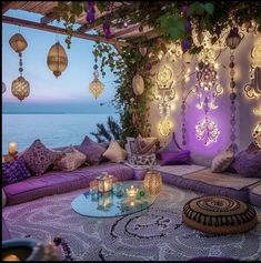 a living room filled with lots of purple furniture and lights hanging from the ceiling above it