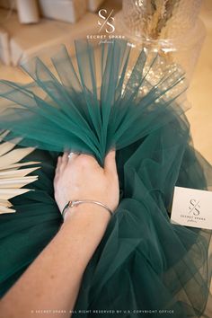 a woman in a green dress is holding onto a large piece of material with her hands