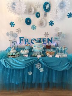 a frozen birthday party with blue and white decorations on the wall, table clothed in snowflakes