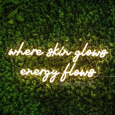 a neon sign that reads, where the sky glows energy flows in front of some green plants