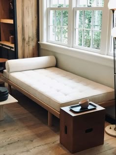 a white couch sitting next to a window in a room with wooden floors and walls