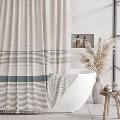 a bath tub sitting next to a shower curtain in a white bathroom with gray and blue accents