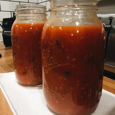 two jars filled with sauce sitting on top of a counter