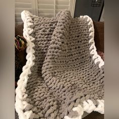 a gray and white crocheted blanket sitting on top of a couch