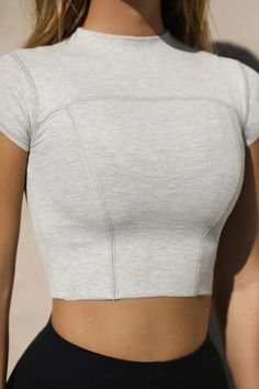 Fitted crop tee with cap sleeves, stitch detailing, and a mini mock neckline. Feel a subtle pop of texture in this tight-knit ribbed fabric. It's stretchy, comfortable, and forms perfectly to your body. Color: Pearl Grey Rib Sizing: X/S (0-2), S/M (4-6), M/L (8-10) Model is 5'8" and is wearing size X/S Fabric: 95% Ribbed Rayon, 5% Spandex Care: Machine wash cold with like colors. Lay flat to dry. Knit Fabric Tops, Seamless Stretch Cropped T-shirt, Fitted Ribbed Short Sleeve Top For Summer, Sporty Fitted Top With Ribbed Neckline, Solid Cropped T-shirt For Athleisure, Solid Athleisure Cropped T-shirt, Cropped T-shirt For Athleisure, Ribbed Stretch Short Sleeve Top For Summer, Stretch Top With Ribbed Neckline And Short Sleeves