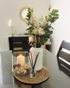 a vase with flowers and candles on a table