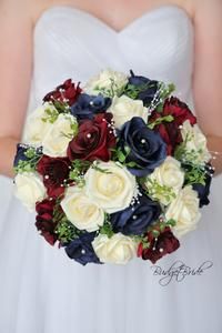 a bridal bouquet with red, white and blue flowers in the bride's hand