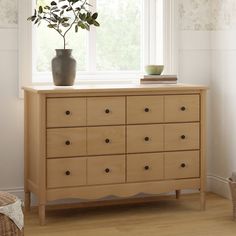 a wooden dresser sitting in front of a window with a potted plant on top