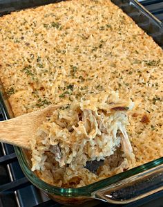 a casserole dish with chicken and rice in it being lifted from the oven by a wooden spoon