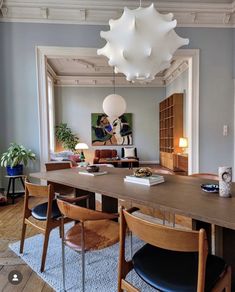 a dining room table and chairs in front of a large window with lots of light