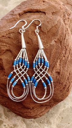 blue and silver earrings sitting on top of a rock