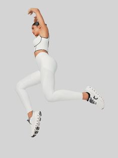 a woman in white is jumping up into the air with her arms out and legs spread wide