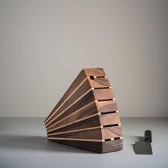 a wooden object sitting on top of a table next to a small piece of wood