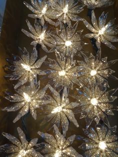 a lighted christmas tree with snowflakes hanging from it's sides