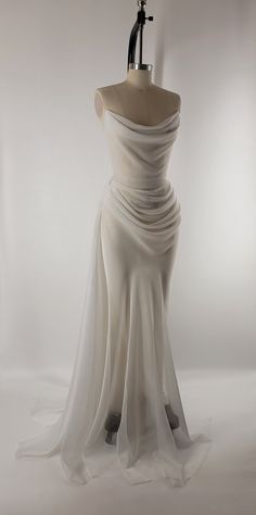 a white dress is displayed on a mannequin with an object in the background