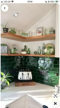 a kitchen with green tiles on the wall and wooden shelves in front of the stove