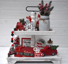 three tiered tray with christmas items on it and decorations around the bottom shelf,