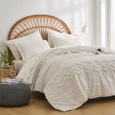 a bed with white sheets and pillows in a room next to a wicker headboard