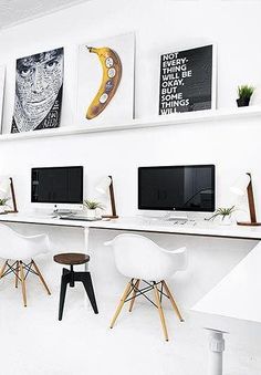 an office with three computer screens on the wall