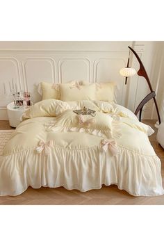 a white bed with ruffled bedspread and pillowcases on the floor