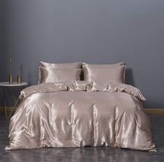 a bed that has some pillows on top of it and is in front of a gray wall