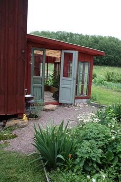 a small red shed sitting on top of a lush green field