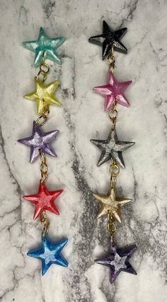 six star shaped keychais on a marble counter with the colors of rainbow and gold