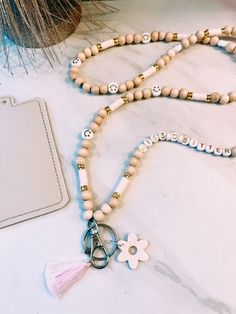 a necklace with beads and charms sitting on a table next to a card holder, scissors and a clipboard