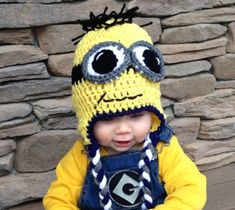 a small child wearing a crocheted hat and overalls