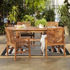 an outdoor dining table with chairs and potted plants