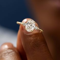 a woman's hand holding an oval diamond ring