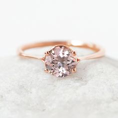 a pink diamond ring sitting on top of a rock