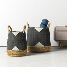 two woven baskets sitting next to each other on top of a white floor near a couch