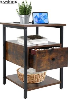 a wooden table with drawers and a laptop on top, next to a potted plant