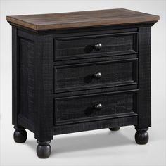 a black night stand with three drawers on wheels and a wooden top, against a white background