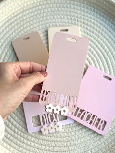 a person holding up some pink and white tags on top of a plate with flowers