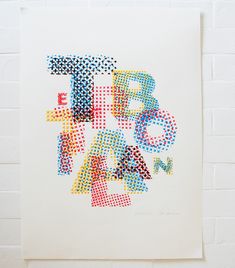 an abstract painting made up of different colored dots and letters on a white paper background