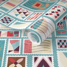 a roll of fabric on top of a quilted tablecloth with various designs and colors